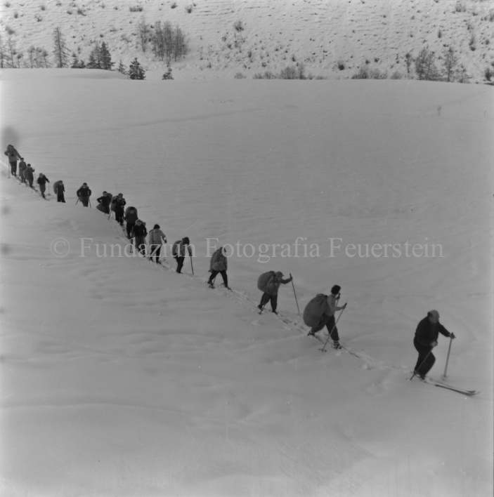 Kolonne von Skitourengängern mit Strohsäcken