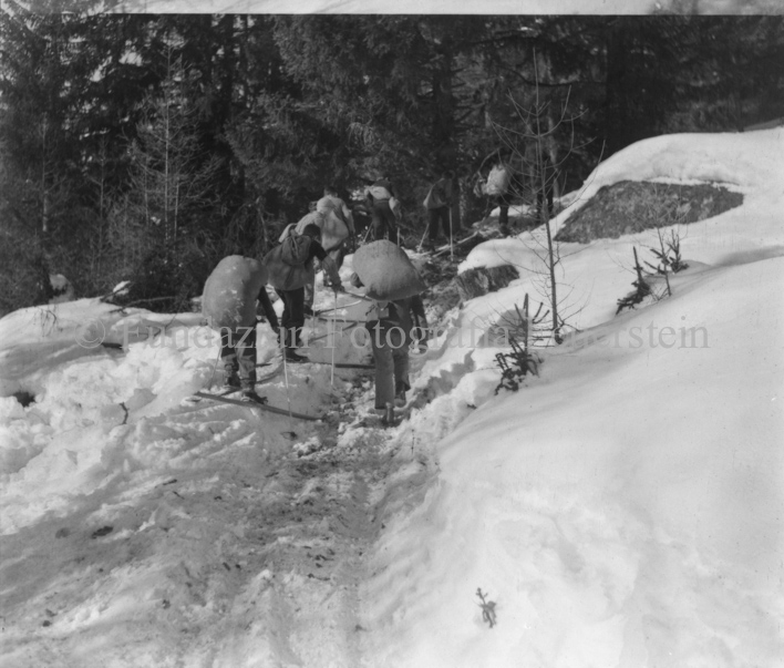 Skitourengänger mit Strohsäcken auf verschneitem Waldweg