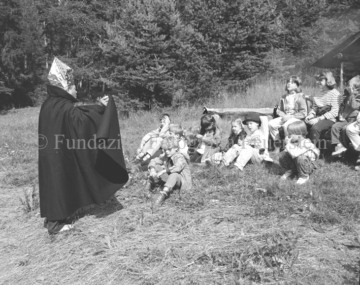 «Märchenprinz», Mann im Zaubererkostüm mit Kindergruppe bei Lagerfeuer bei Waldhütte
