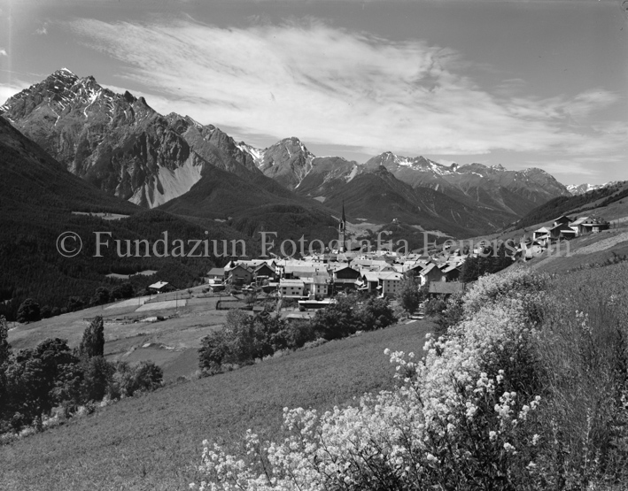 Dorfansicht Sent mit Kirche und Berglandschaft, Blumen im Vordergrund