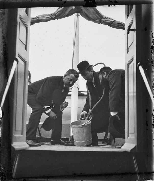 Drei Männer auf einem Segelschiff mit einem Kübel