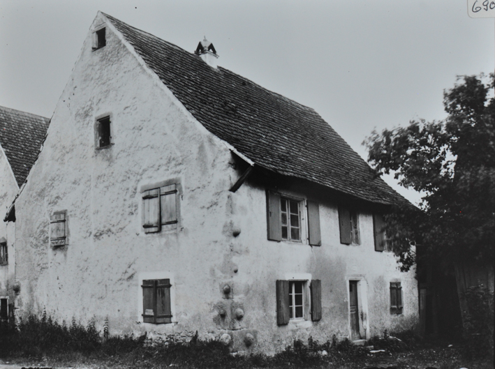 Zweistöckiges gemauertes Wohnhaus mit Satteldach und Kamin, rechts neben dem Haus belaubter Baum