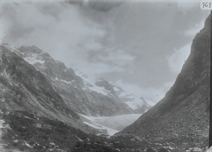 Landschaftsaufnahme einer verschneiten Bergkette sowie eines Gletschers, Himmel bewölkt