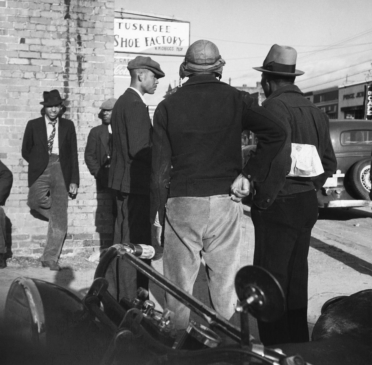 Deutsch: USA, Tuskegee/AL: Menschen; Männer wartend neben einem Gebäude mit der Anschrift Shoe FactoryEnglish: USA, Tuskegee/AL: People; Men waiting beside a building with the address "Shoe Factory"