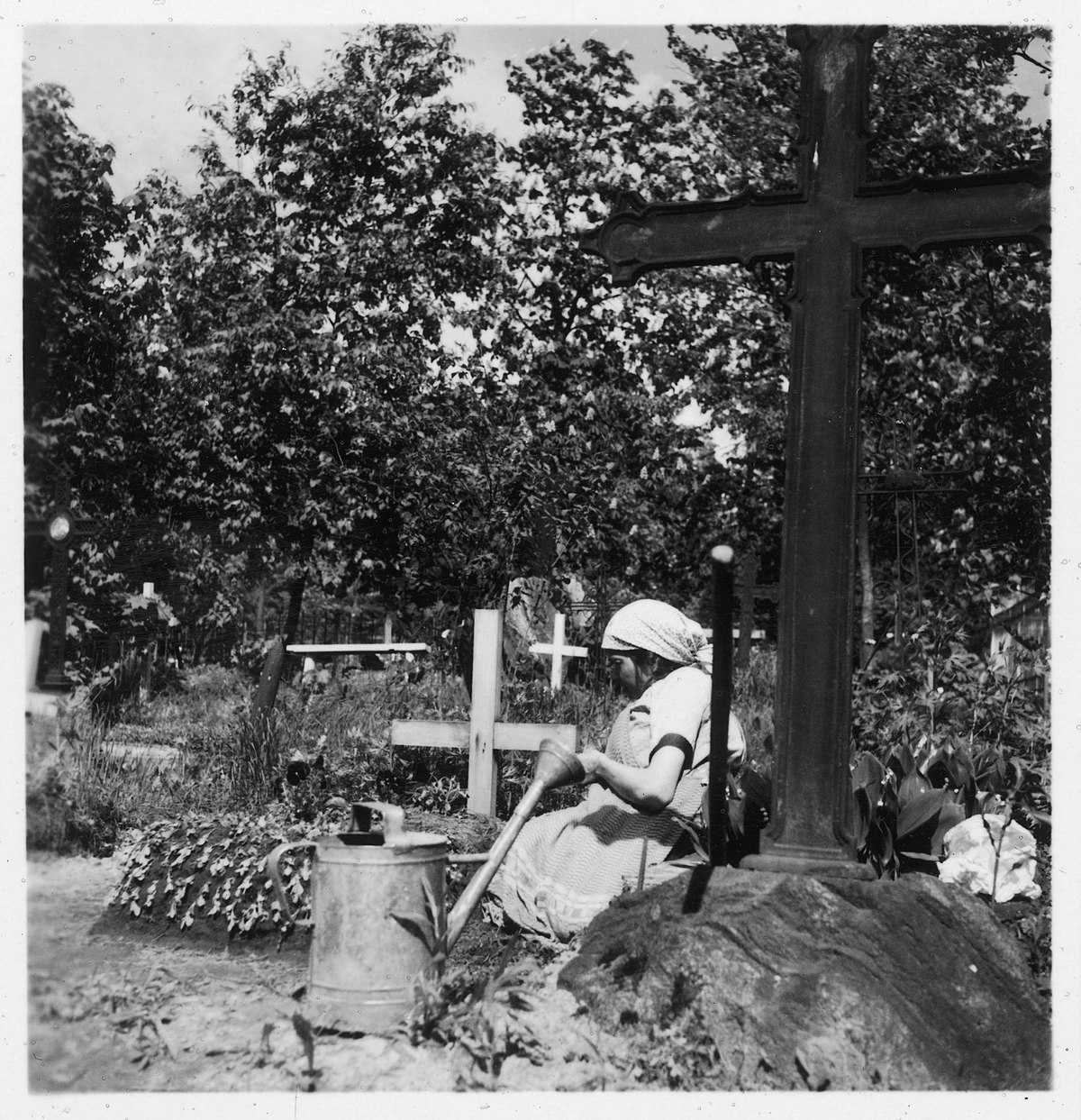 Estland, Valk/Walk (Valga): Friedhof; Frau sitzend neben den Gräbern