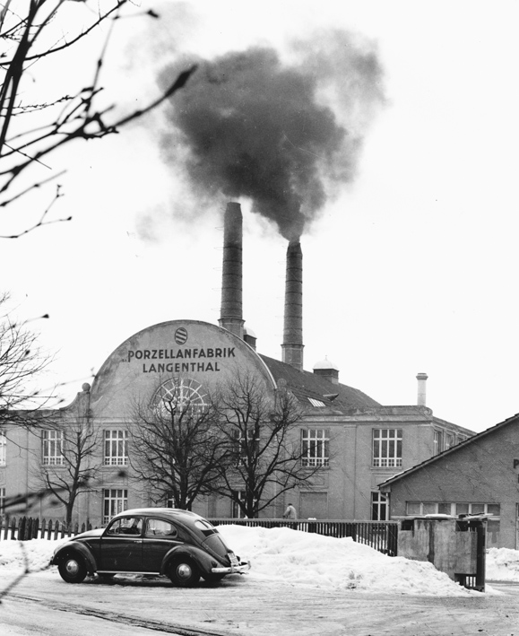 Fabrikgebäude mit rauchendem Kamin und Auto (VW-Käfer),
   gehört zu Dossier: Porzellan-Fabrik mit Besuch von Henri Guisan