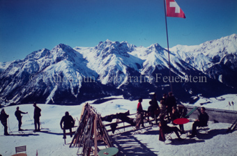 Personen neben Skipiste und auf Terrasse