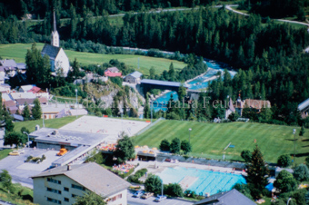Blick auf Dorf Scuol mit Sportanlage Trü, Kirche und Holzbrücke