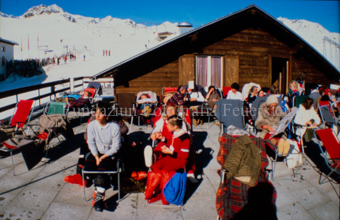 Personen auf Sonnenterrasse neben Skipiste