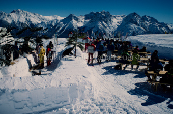 Personen an Tischen im Schnee, künstliche Palmen und Kokosnüsse