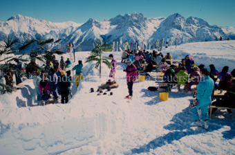 Personen an Tischen im Schnee, künstliche Palmen und Kokosnüsse