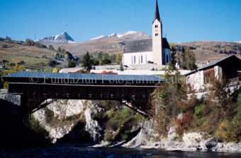 Blick auf Kirche und Holzbrücke vom Inn im Herbst