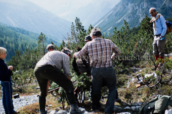 Drei Jäger laden erlegten Steinbock auf Karren