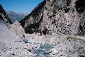 Postauto der PTT «S-charl - Scuol» auf Bergstrasse neben Bach