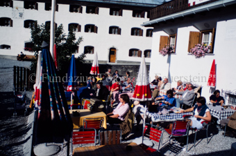 Restaurantterrasse in S-charl, Personen an Tischen mit Bunten Sonnenschirmen