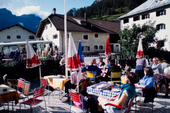 Restaurantterrasse in S-charl, Personen an Tischen mit Bunten Sonnenschirmen