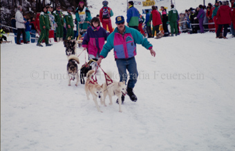 Alpirod Hundeschlittenrennen, Gespann im Ziel «Böt», Mann und Frau führen Hunde
