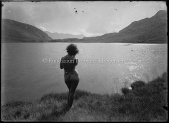 Frauenakt an einem Bergsee, Rückenansicht, Blickrichtung See