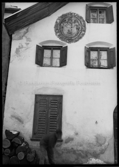 Aussenansicht Haus, «Wappen Bisaz» ziert Fassade, Mann steht vor dem Haus