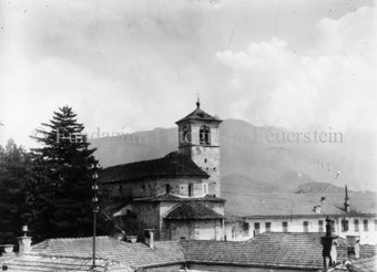 Siedlungansicht mit Kirche und Bergen im Hintergrund