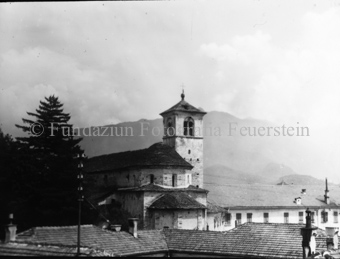 Siedlungansicht mit Kirche und Bergen im Hintergrund