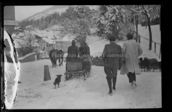 Personengruppe mit Pferdeschlitten, Kühen und Hund