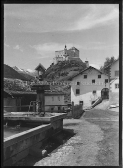 Blick von Dorfplatz mit brunnen auf Schloss Tarasp
