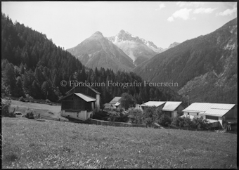 Häusergruppe auf Ebene, Berggipfel im Hintergrund