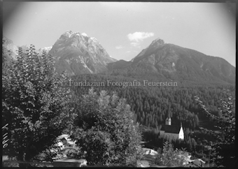 Kirche mit Bäumen und Berg