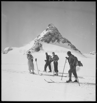 Vier Skifahrer vor Berggipfel