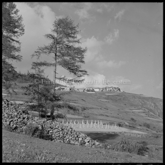 Feld mit Korngarben, dahinter Dorf
