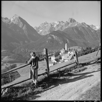 Mädchen an Geländer, Dorf und Berge