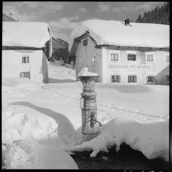 Verschneiter Dorfplatz mit Brunnen