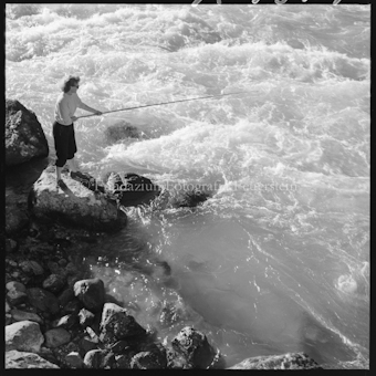 Frau mit Angelrute an Bach