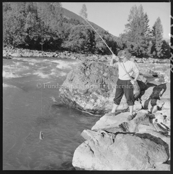 Frau mit Angelrute an Bach