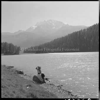 Frau an Seeufer sitzend