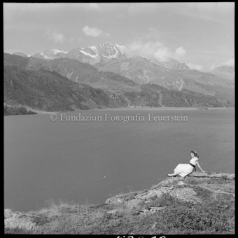 Frau an Seeufer sitzend