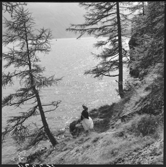 Frau an Seeufer sitzend