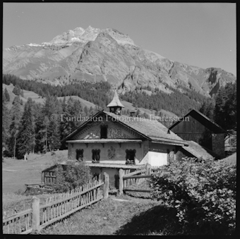 Haus mit Dachreiter vor Berg