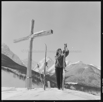 Frau mit Ski in verschneiter Berglandschaft mit Kreuz