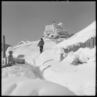 Frau mit Ski in verschneiter Berglandschaft in Richtung Schloss Tarasp