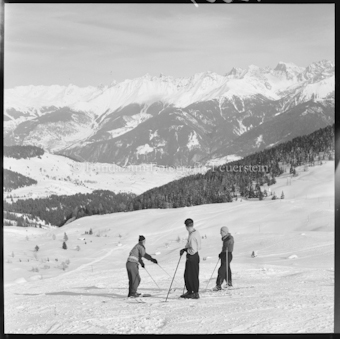 Drei Personen auf Skipiste, verschneite Berglandschaft