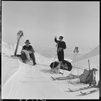 Zwei Personen mit Ski, Stöcken und Rucksäcken
