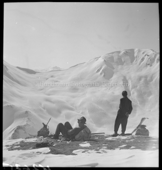 Zwei Personen mit Ski, Stöcken und Rucksäcken