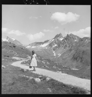 Frau auf Weg durch Berglandschaft, Berggipfel im Hintergrund