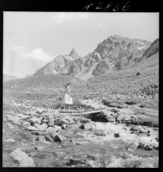 Frau auf Holzbrücke in Berglandschaft