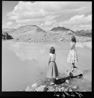 Zwei Frauen auf Steinen vor See