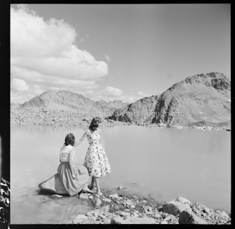 Zwei Frauen auf Steinen vor See