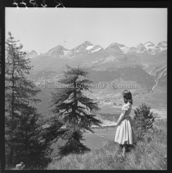 Frau auf Wiese, im Hintergrund Dorf