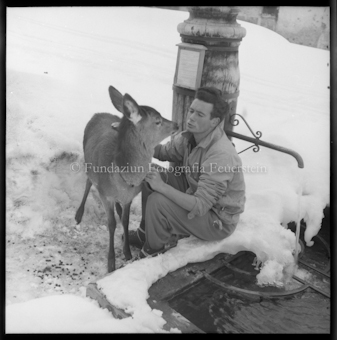 Mann mit jungem Hirsch am Brunnen